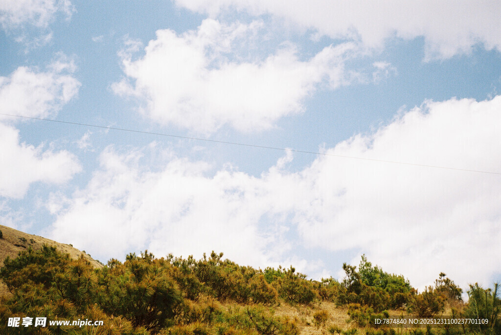 蓝天白云下的葱郁山坡