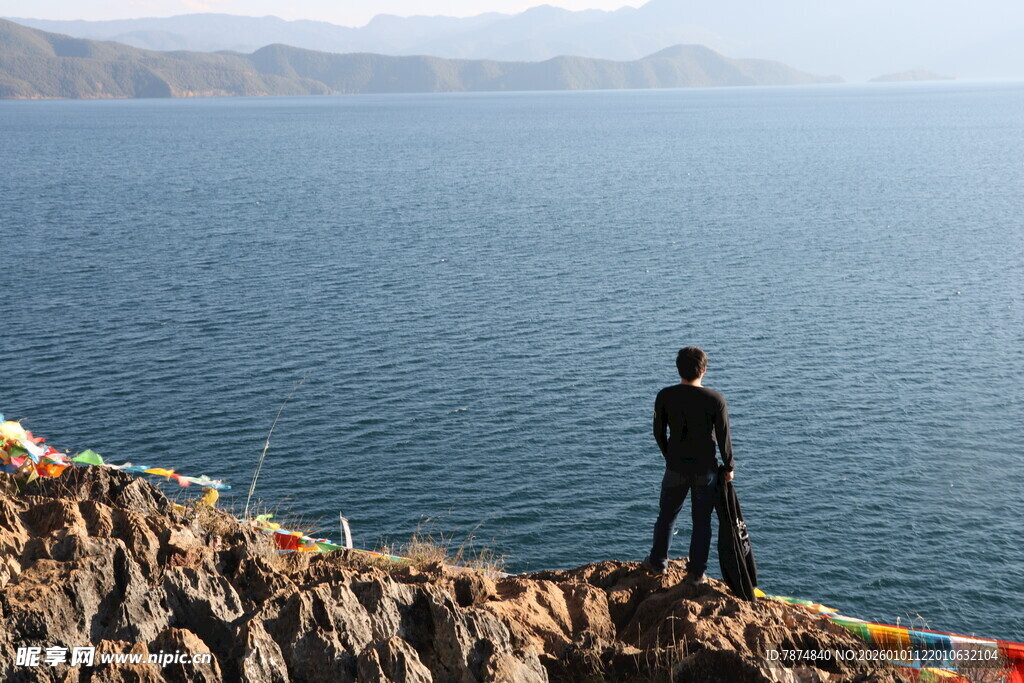 男子立于湖畔岩石赏景