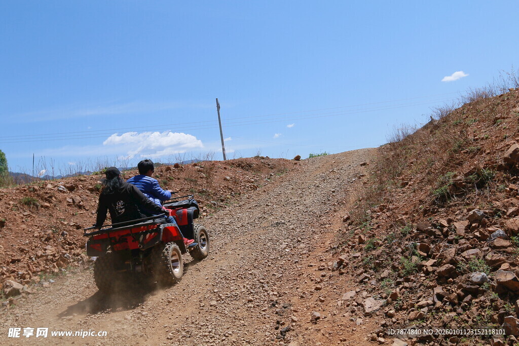 两人驾驶四轮车行驶在土路上