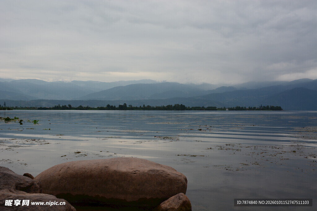 湖畔巨石与远方阴云景色