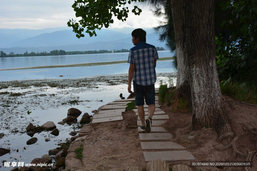 男子漫步于水边木栈道