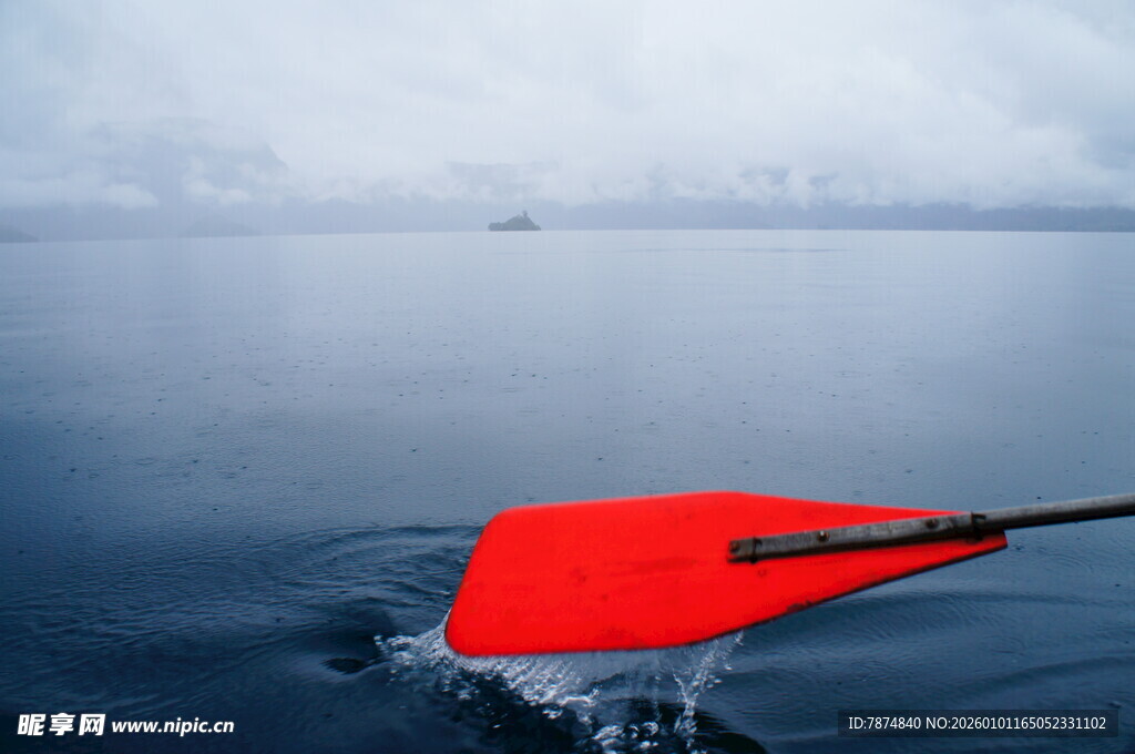 红色船桨划动平静水面