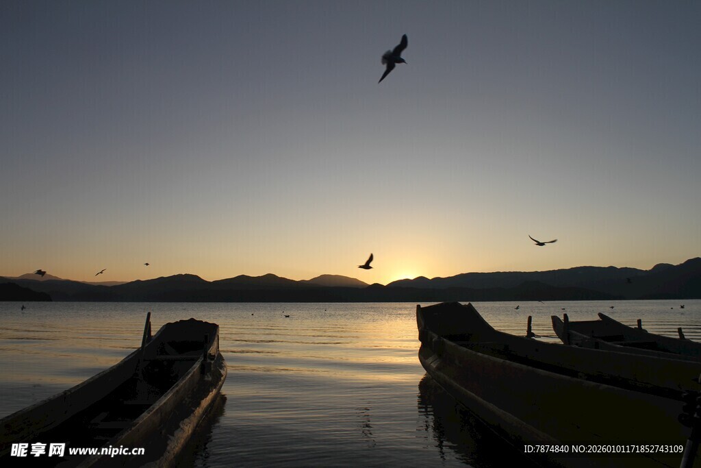 夕阳下湖面的船只与飞鸟