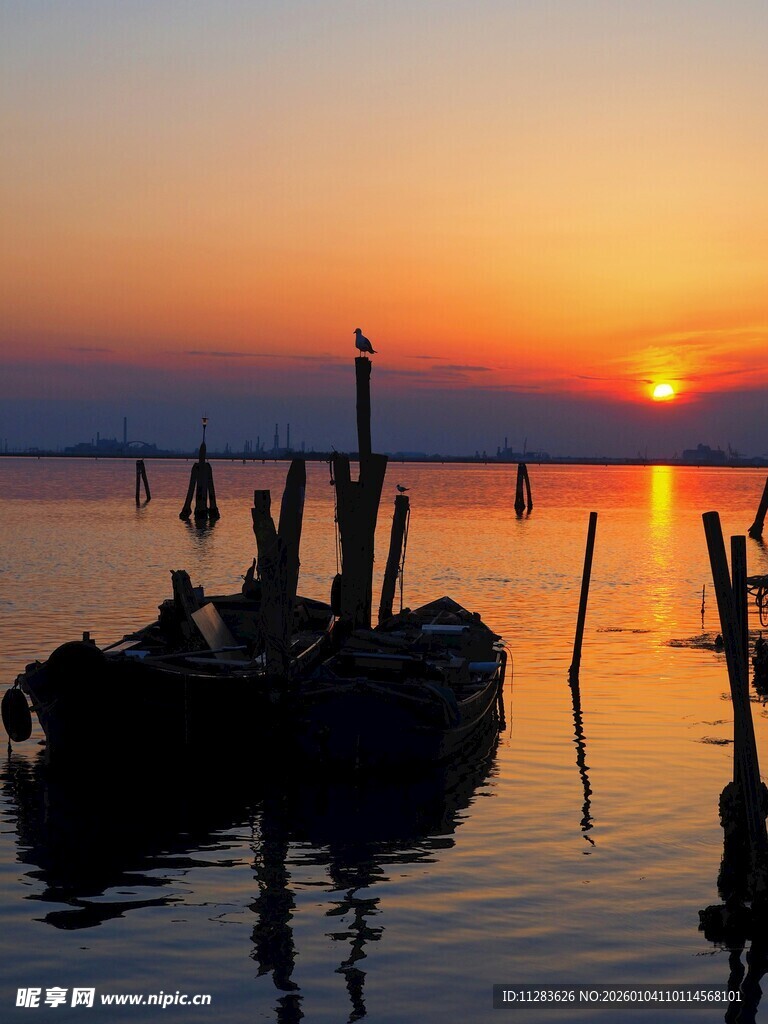 夕阳下的水上木桩与小船
