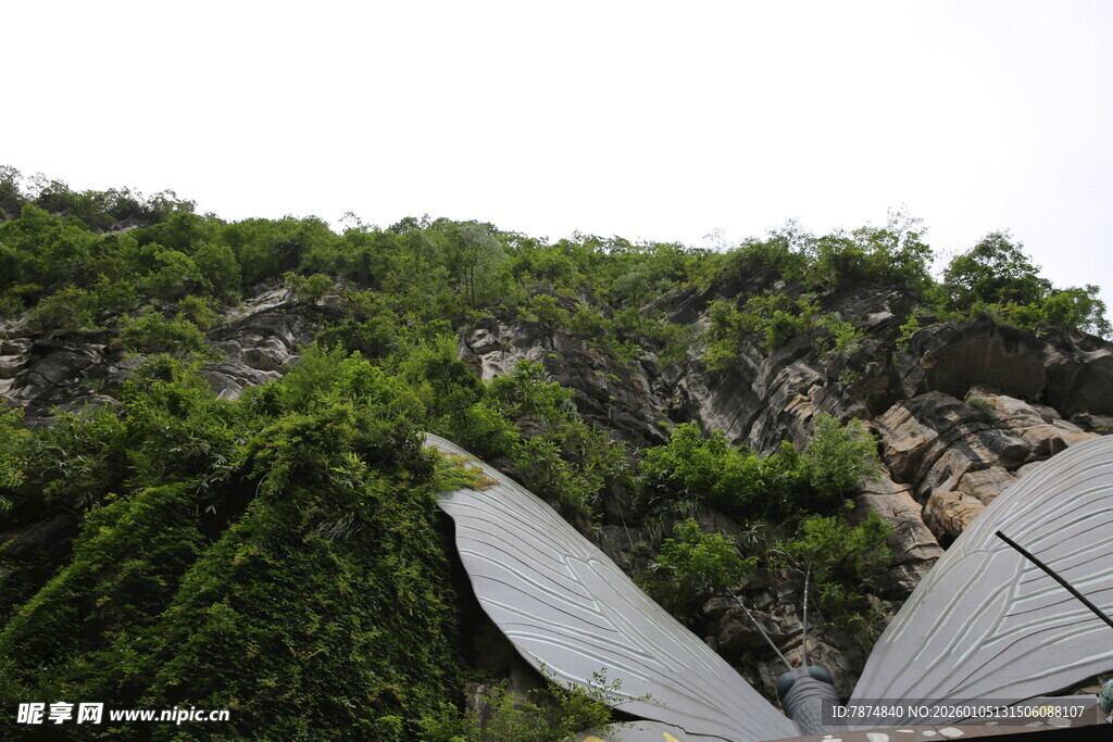 山间羽翼雕塑与葱郁植被