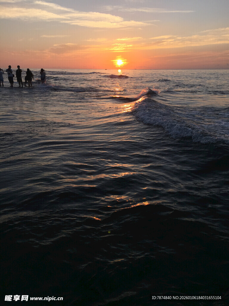 海边日落时的踏浪人群