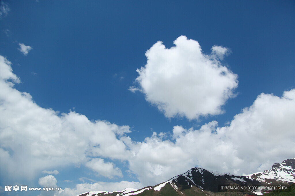 蓝天雪山间的蓬松云朵