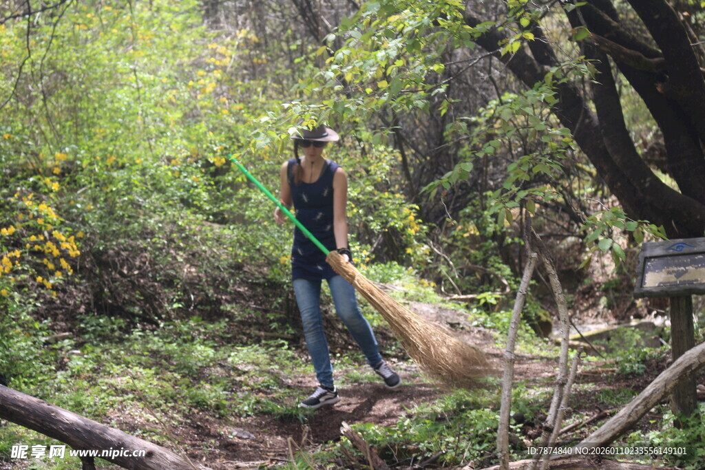 女子林中持扫帚清理杂物