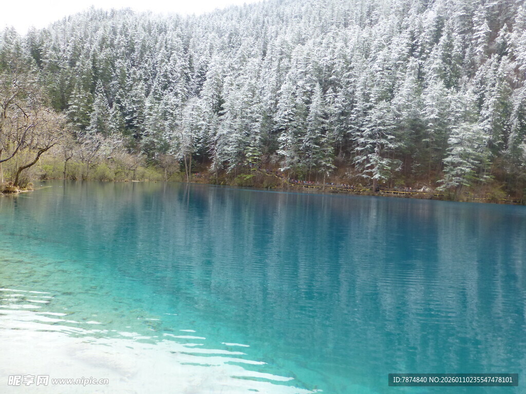 雪覆山林旁的幽蓝湖水
