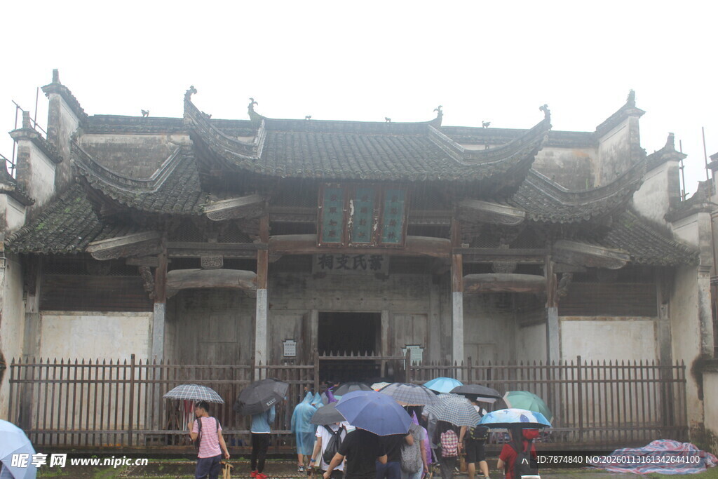 古建前撑伞驻足的人群