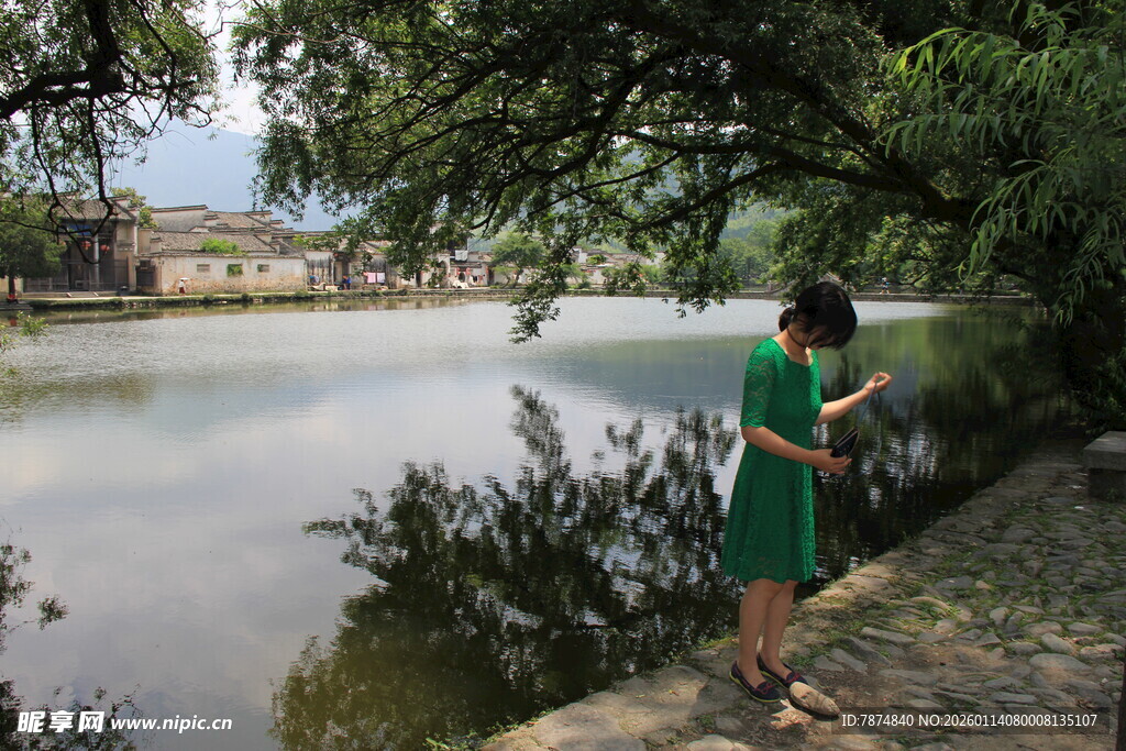 湖畔绿衣女子专注看手机