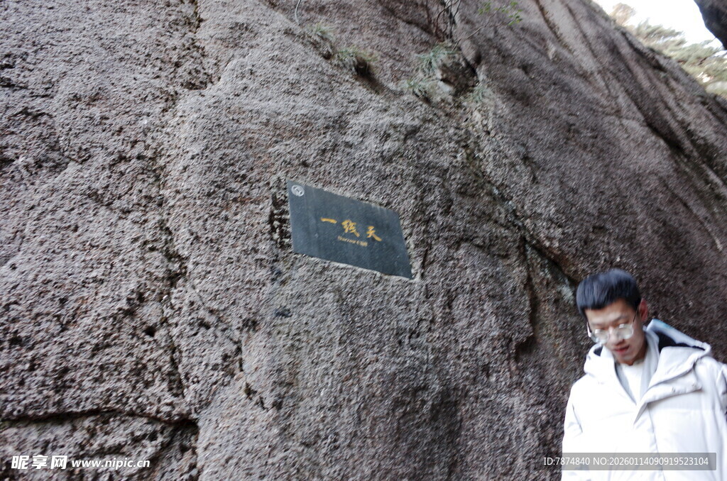 男子立于刻字山石旁