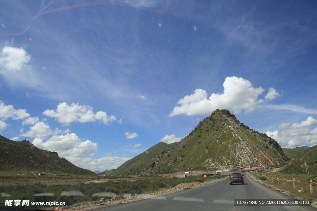 公路穿行于蓝天白云山峦间
