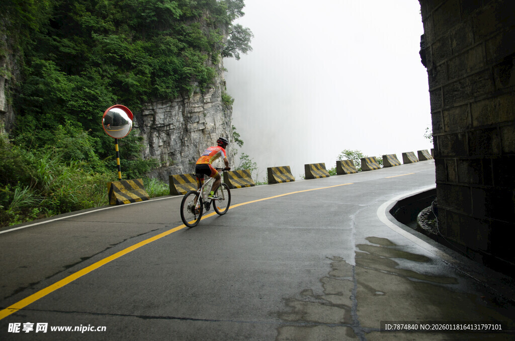 雨中骑行者穿行山间公路