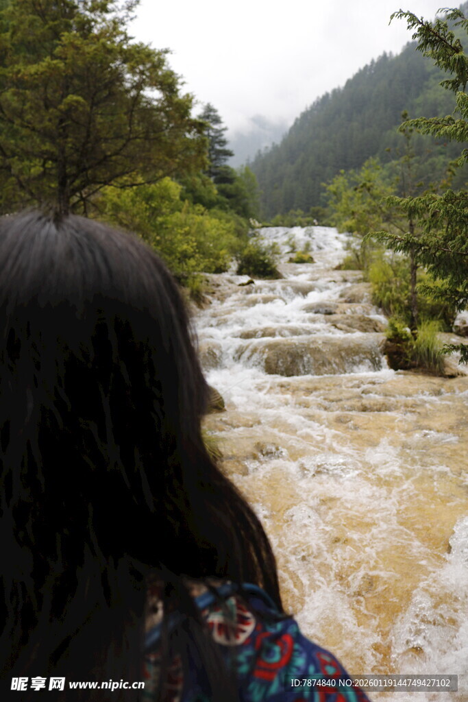 女子赏湍急山间溪流