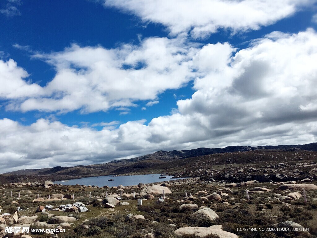 蓝天白云下的湖畔岩石景