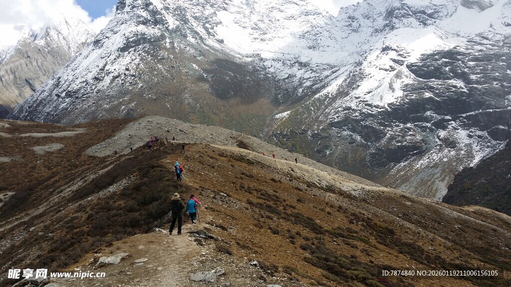 徒步者穿行于雪山山间