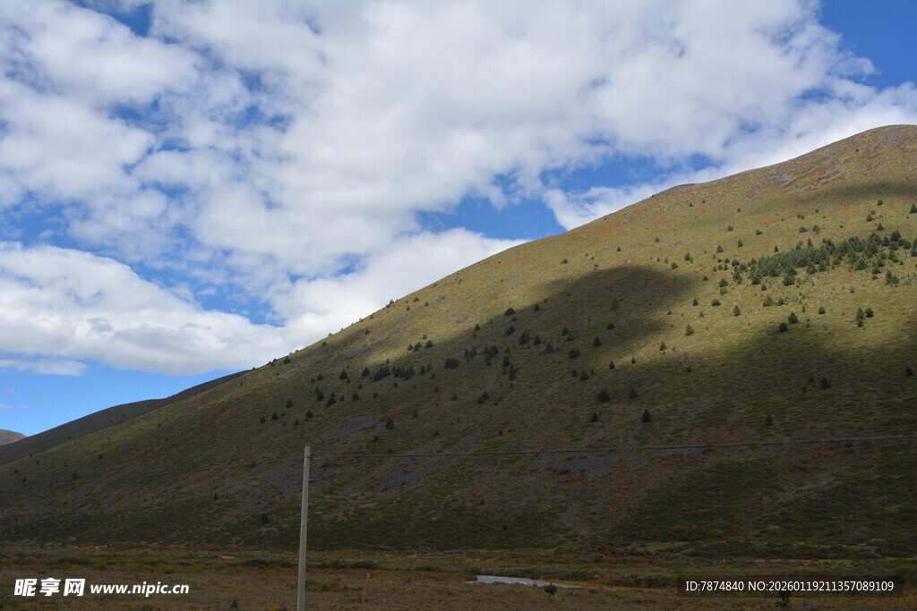 蓝天白云下的翠绿山坡