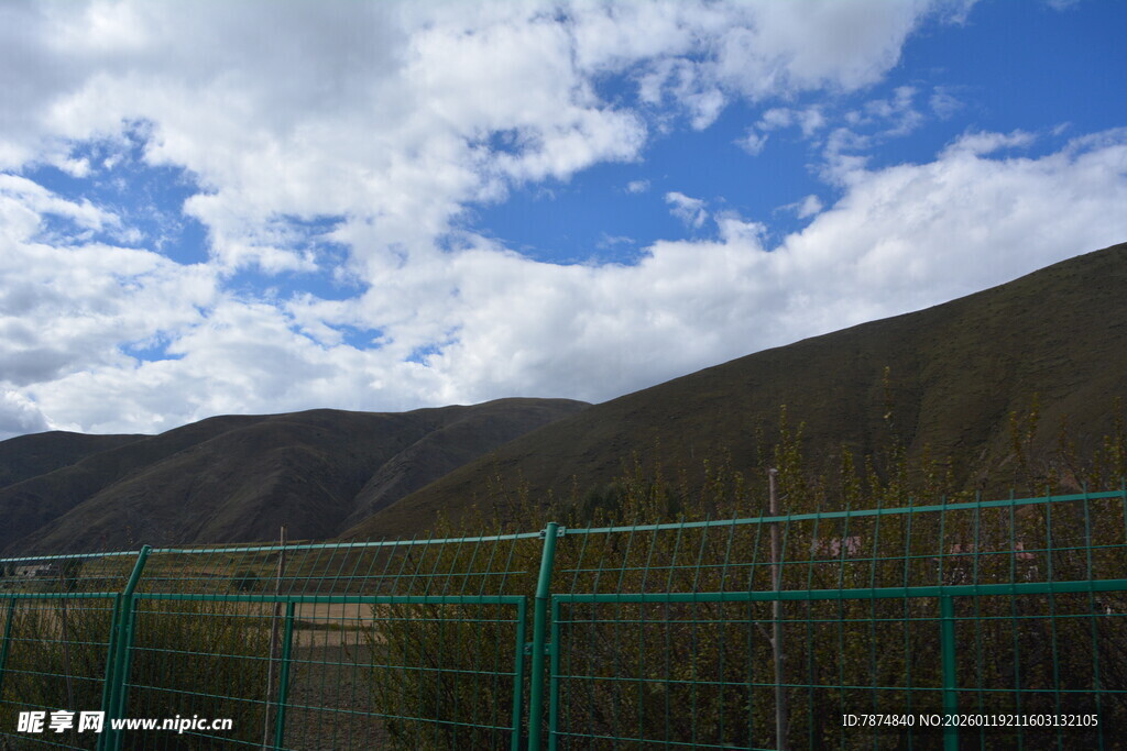 蓝天白云下的山间绿围栏
