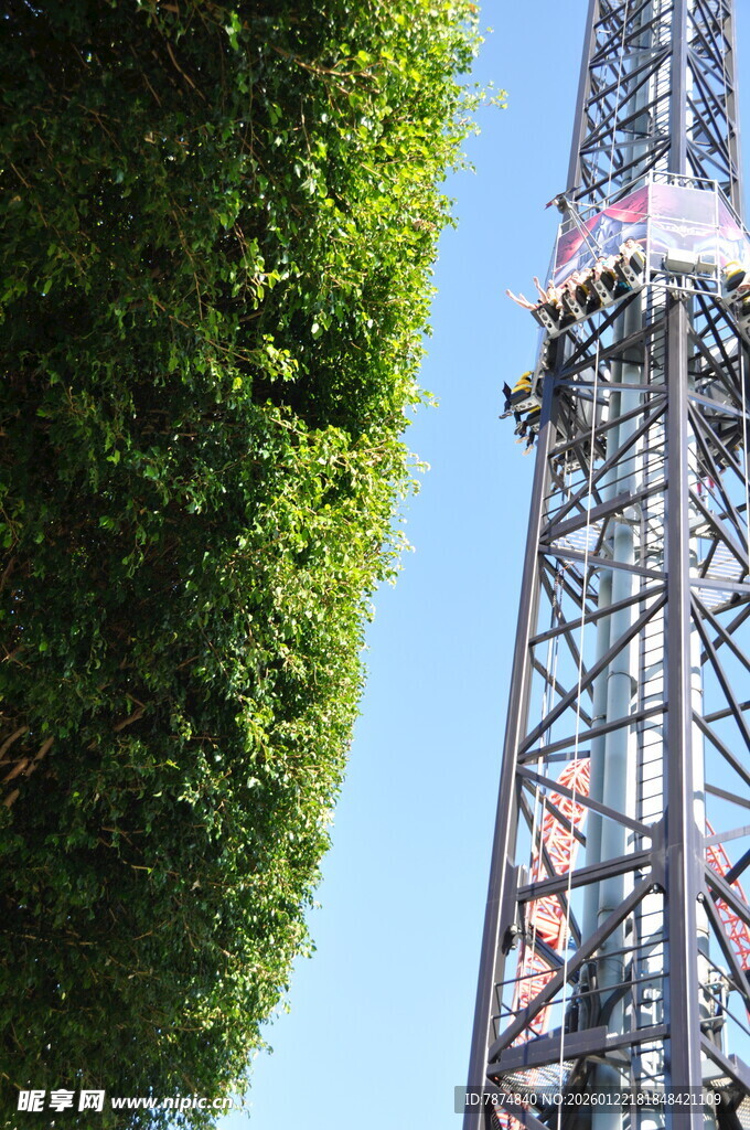 绿树旁的高耸铁塔