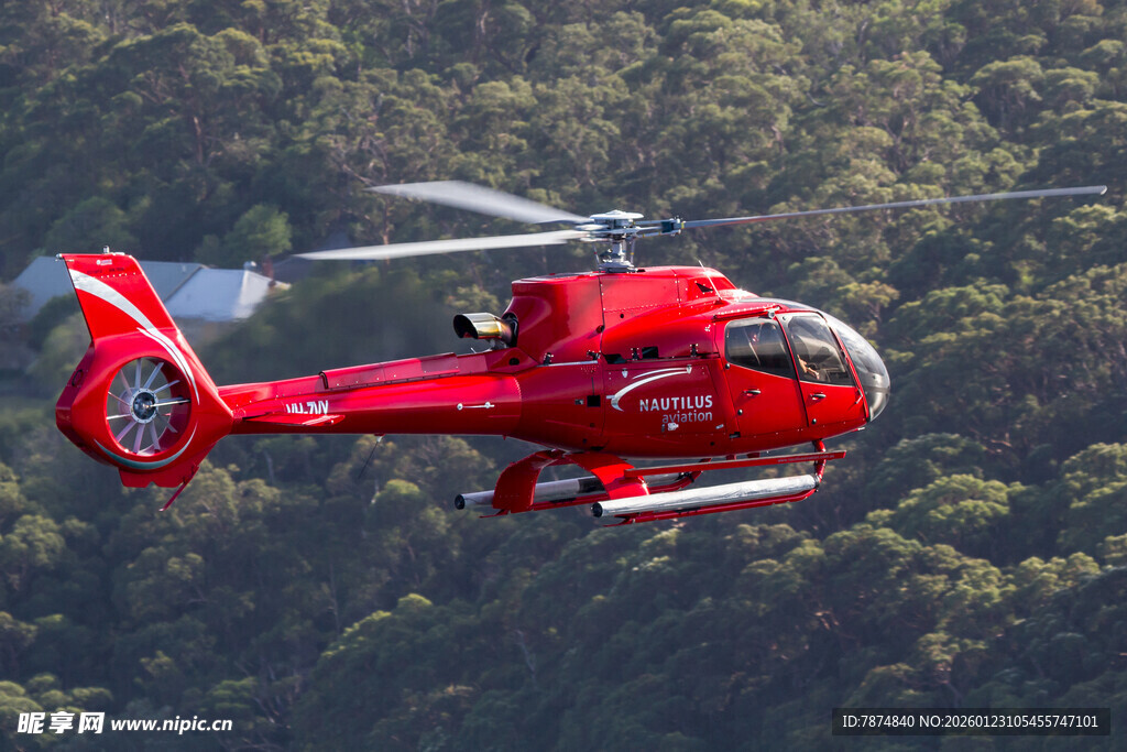 红色直升机翱翔于山林间