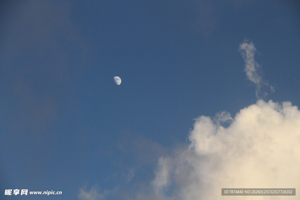 蓝天中云朵旁的一弯新月