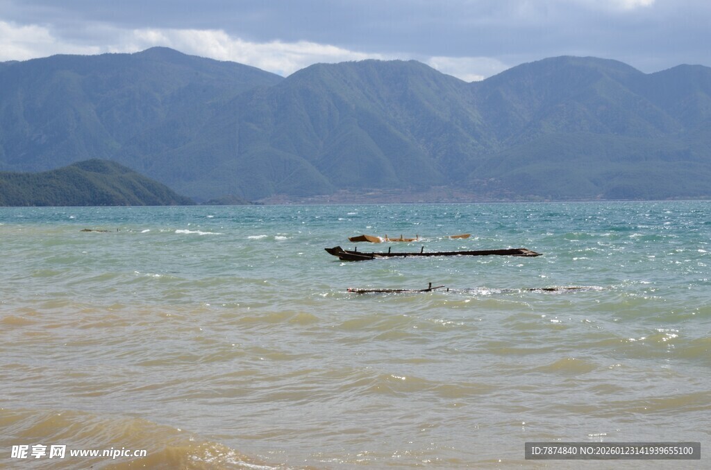 海边浅滩上的小船与远山