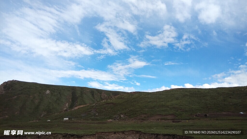 蓝天白云下的翠绿山坡
