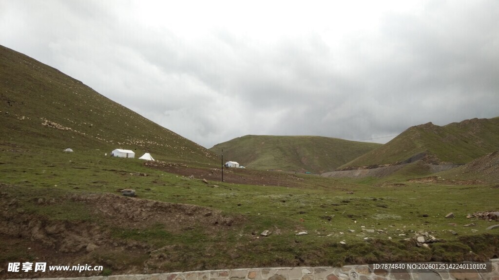山间草地与远处小屋景色