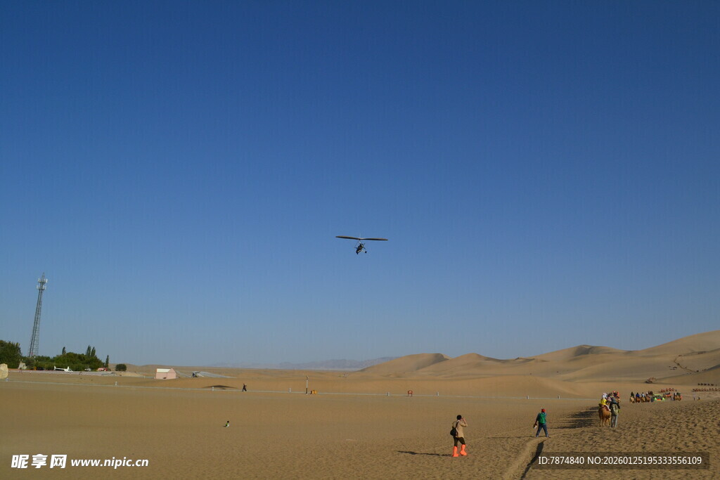 沙漠中人们在蓝天下滑沙