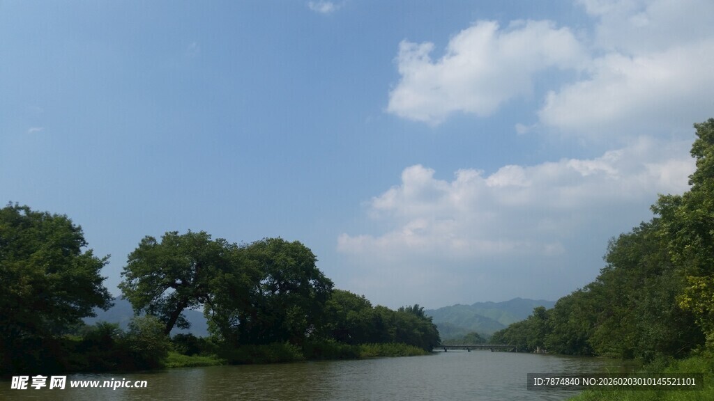 河畔绿树蓝天风景图