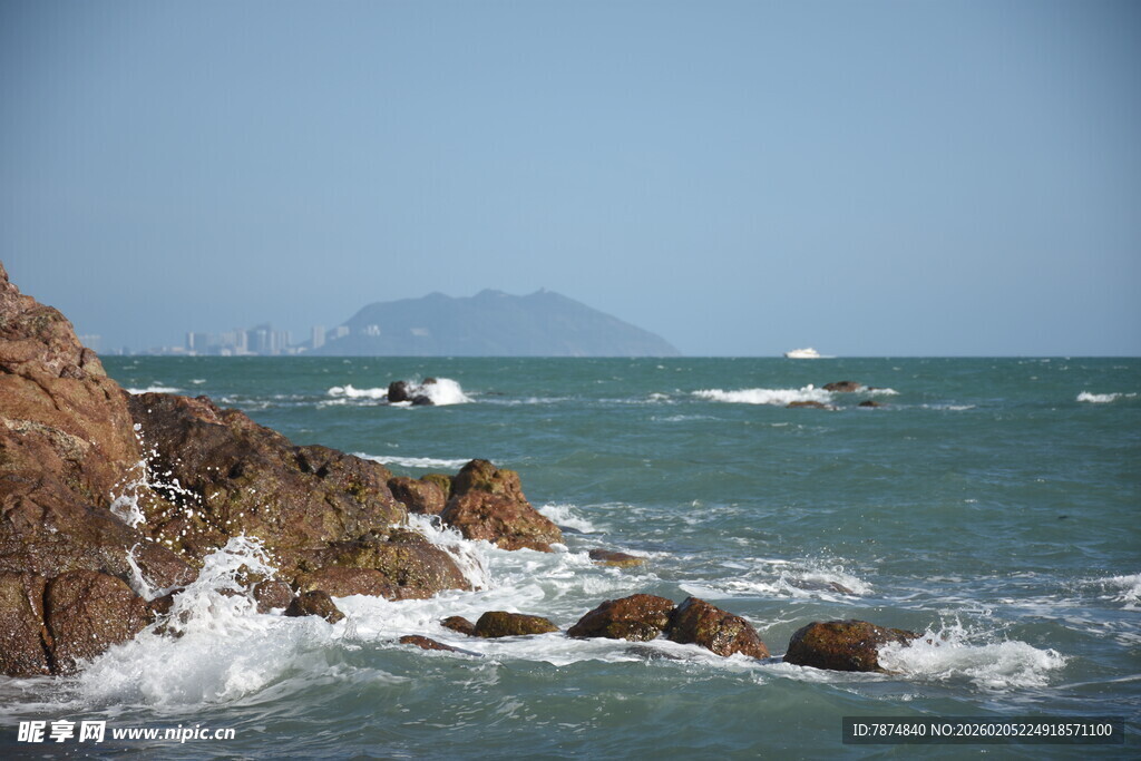 三亚海边礁石旁的海浪与船只