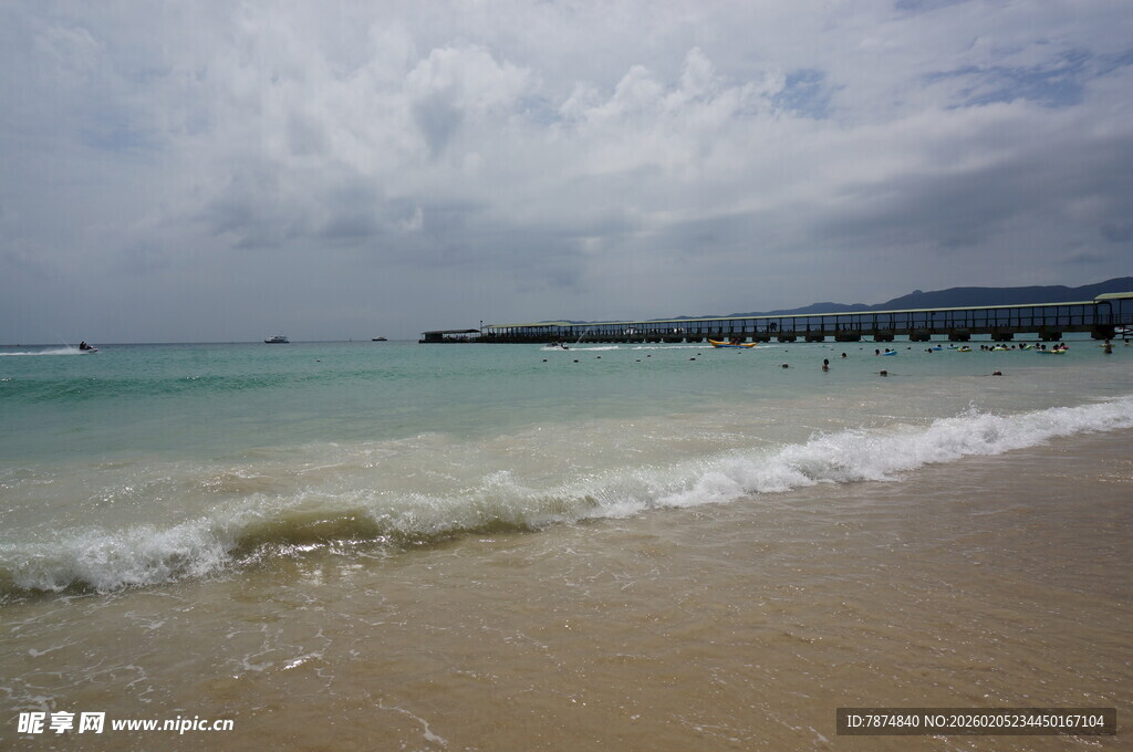 三亚海边沙滩海浪与远处桥梁