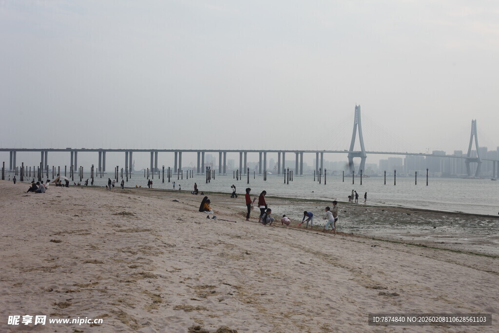 湛江江边沙滩上的行人与大桥