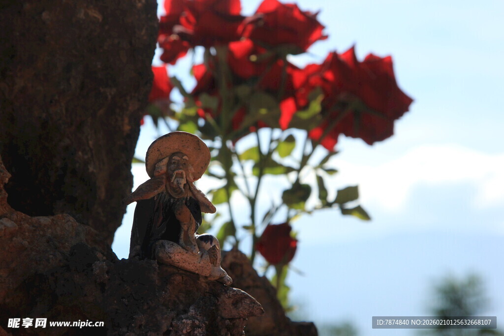 红玫瑰旁的可爱小雕像