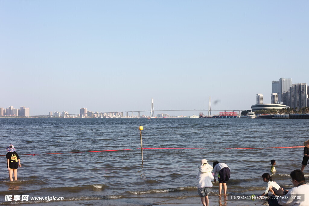海边游玩的人群与城市远景