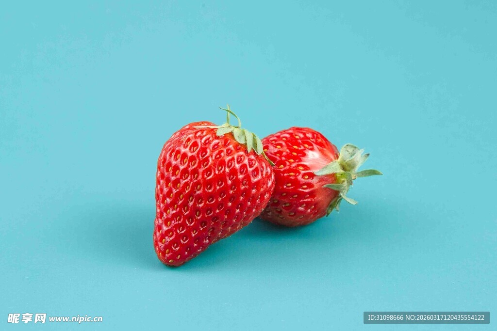 两颗鲜红草莓置于蓝背景
