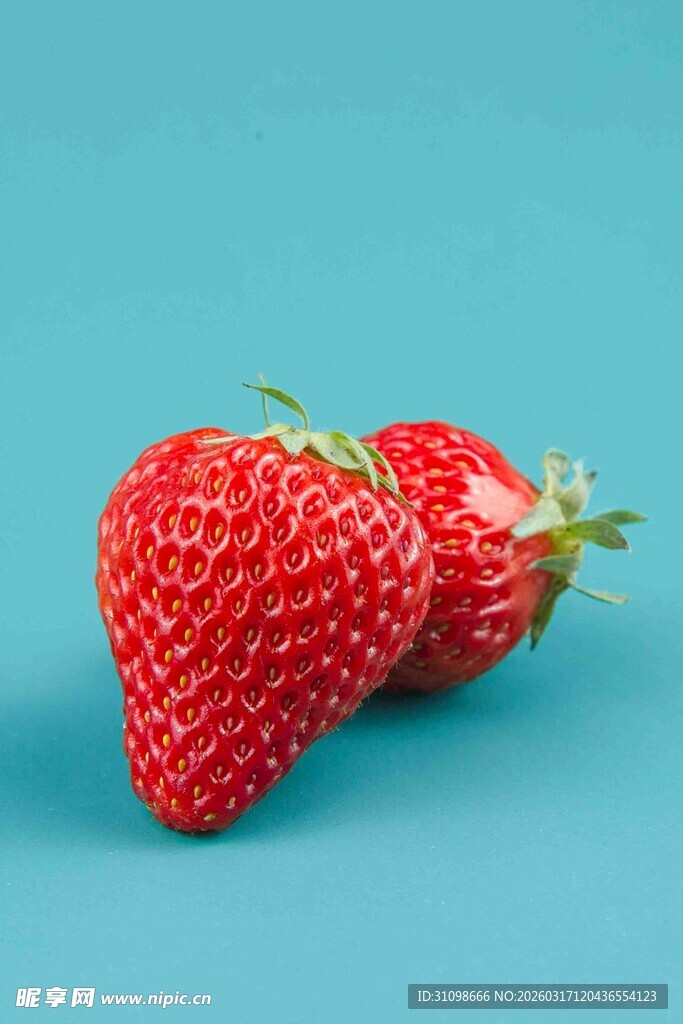 两颗鲜草莓置于蓝背景