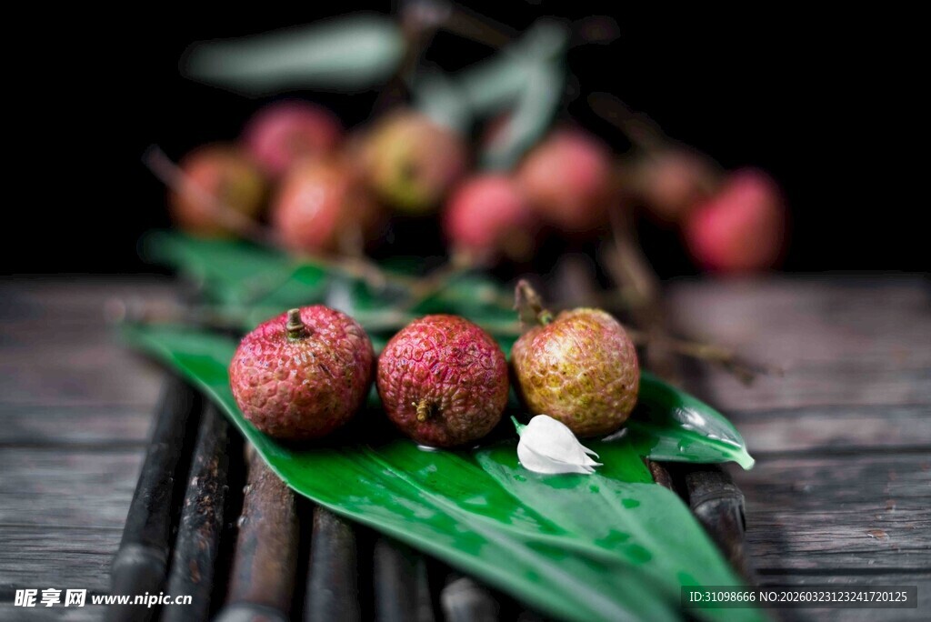 新鲜荔枝摆于绿叶竹席上