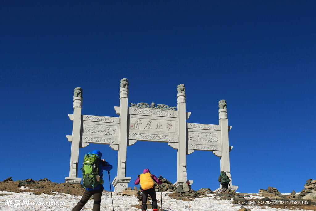 登山者前行于古朴牌坊下