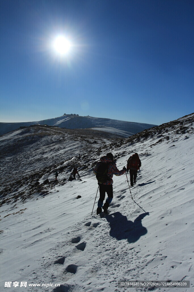雪地徒步者沐浴阳光前行
