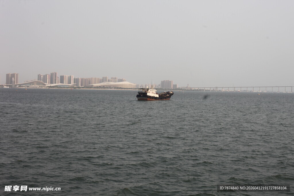 湛江海上孤舟与远处城市景观