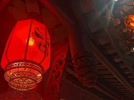 中式建筑下的红色脸谱灯笼