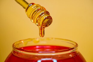 蜂蜜正缓缓滴入玻璃罐中