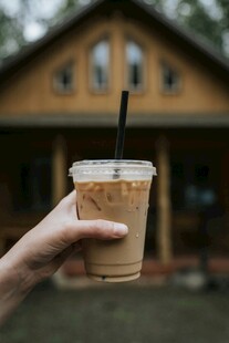 手持冰咖啡与温馨小屋