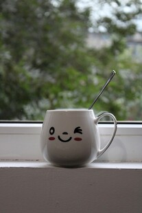 可爱笑脸马克杯置于窗边
