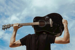 男子扛吉他于蓝天白云下