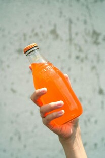 手捧橙色玻璃瓶饮料