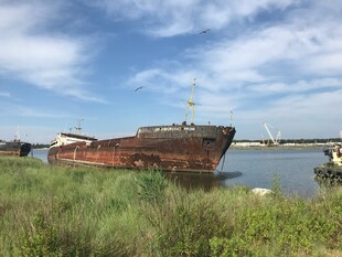 废弃船只静立水边草地