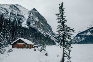 雪中山间小屋与挺拔松树